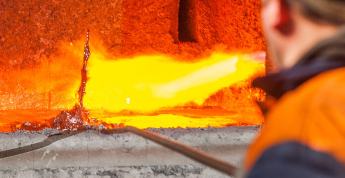 smelter Smelter worker uses tool to prod molten aluminium in furnace