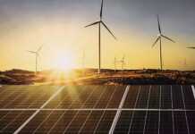 Hydro Tasmania calls for new wind and solar projects wind farm with solar panels in foreground and beautiful sunset in background