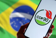 As global climate action threatens to stall, can Australia step up at COP30 in Brazil? Hand holding a smartphone with COP30 logo in front of Brazilian flag