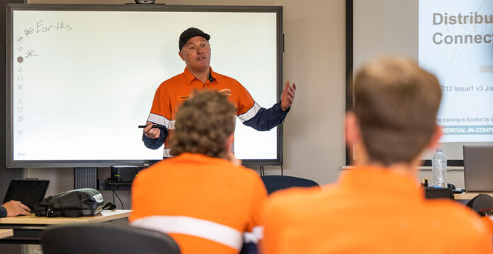 Male trainer and students in high-vis work shirts in a classroom setting