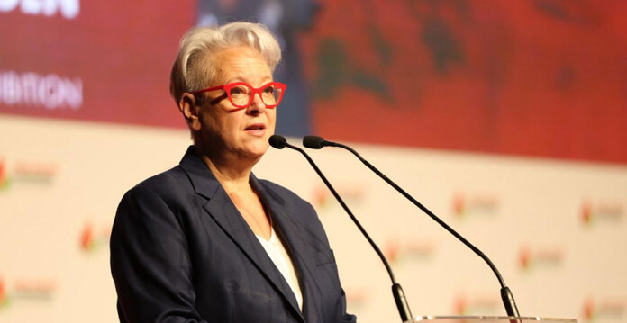 Female government minister in suit delivers speech at conference lectern