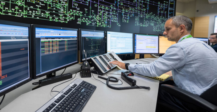transgrid-control-room Transgrid employee sits at control room desk with computer monitors