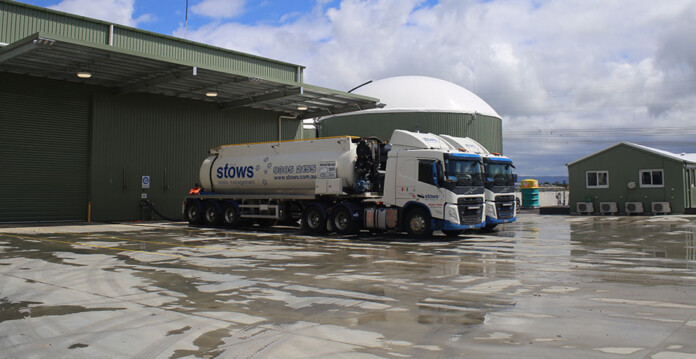 Two large container trucks parked outside industrial facility