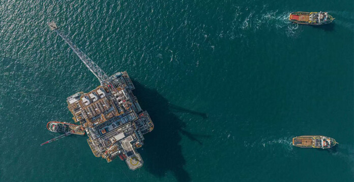 Aerial shot of a massive floating gas production unit being towed by tugboats