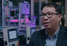 Aussie bushfire prevention technology goes global Man wearing glasses and a suit sits in computer lab illuminated by purple and blue lighting