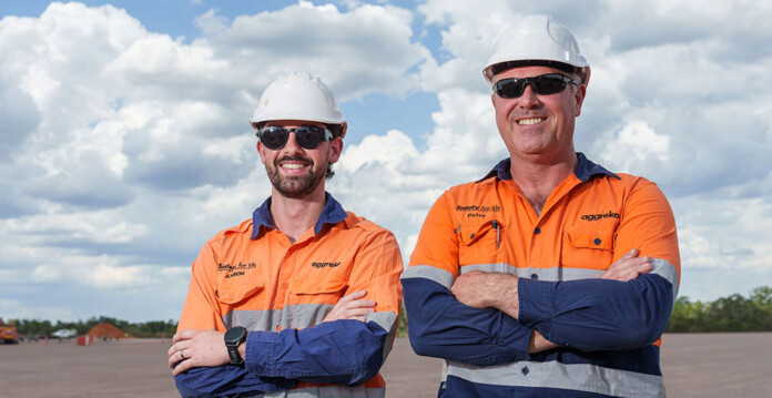 aggreko-hybrid-site Two male workers in high-vis shirts and white hard hats stand with arms folded for photo at gas project site