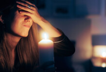 Disconnection policy can prioritise support over punishment Stressed woman covers eyes while holding lit candle in darkened room