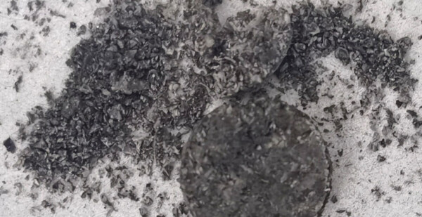 Black granules of graphene spilled onto a white surface