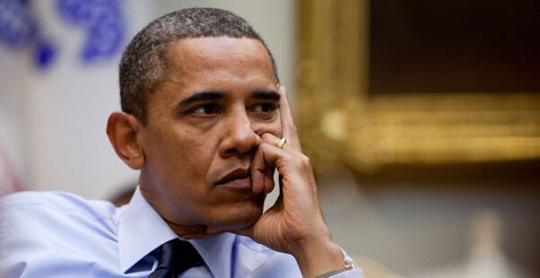 Close-up of former US President Barack Obama in the Oval Office with his hand on his chin 