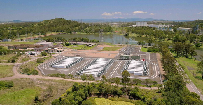Aerial photo of large-scale battery storage project with mountains in background and blue sky overhead