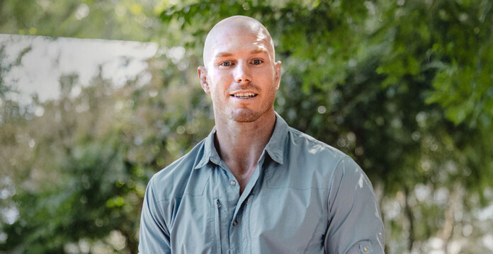 Photo of smiling senator David Pocock with trees and shrubs in background