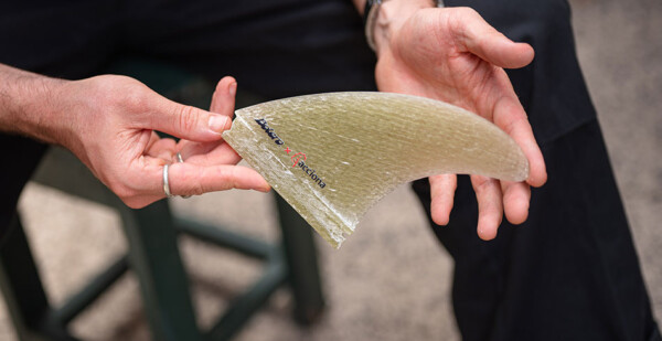 Close up of man's hands holding a surfboard fin