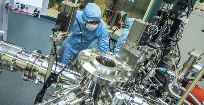 Scientist in blue protective suit and headwear works in quantum battery fabrication lab