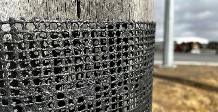 fireproof-mesh Close-up of black fire-proof mesh wrapped around a timber power pole