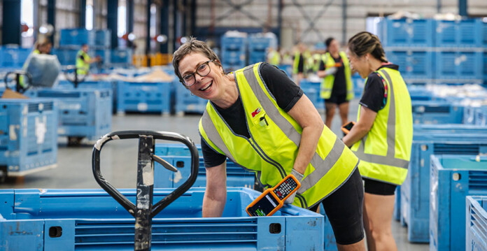 Kmart employees in high-vis yellow vests load pallets in warehouse