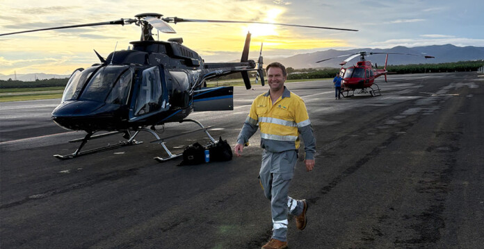 Energy field worker walks toward helicopter at a regional airport with sunrise in background