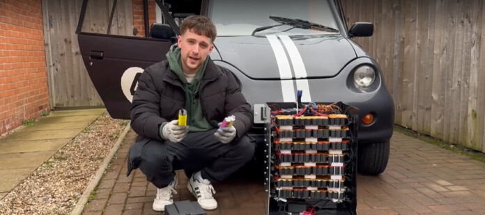 A man poses in front of a tiny electric car with a homemade battery pack made from discarded vapes