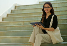 Why digital inclusion is essential among energy providers Female university student sits on steps holding a bag and tablet device