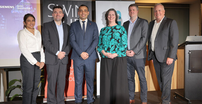 Six researchers and executives pose for photo in front of Swinburne and Siemens signage at event