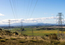 TasNetworks reaches financial close on NWTD project Transmission towers in grassy rural area with blue sky overhead