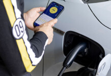 Amber announces Australia’s largest residential V2G rollout White electric vehicle charges while person holds smartphone with charging app on the screen
