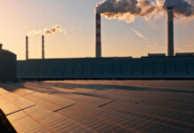 Study finds coal pollution affects solar power output Solar panels in front of coal-fired power plant with smoke pouring from chimneys