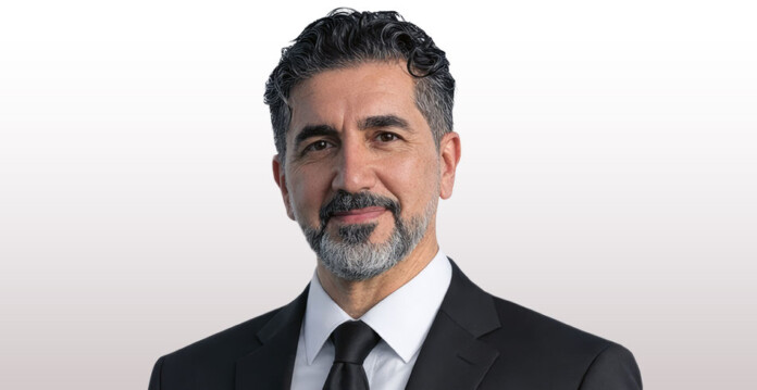 Head and shoulders shot of smiling man wearing a black suit and a tie