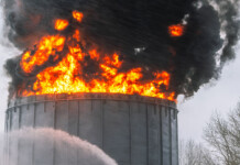 Oil refineries are catching fire in war or by accident. How does this worsen the energy crunch? Flames and black smoke pour from oil refinery storage tank, with stream of water underneath
