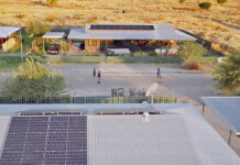 Solar delivers savings for remote Kimberley communities Aerial photo showing solar installation on rooftops in a remote community, with children playing soccer in the street