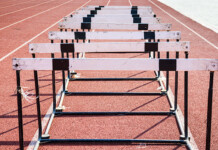 The renewables transition—falling between the hurdles Close-up shot of hurdles set up on a red running track