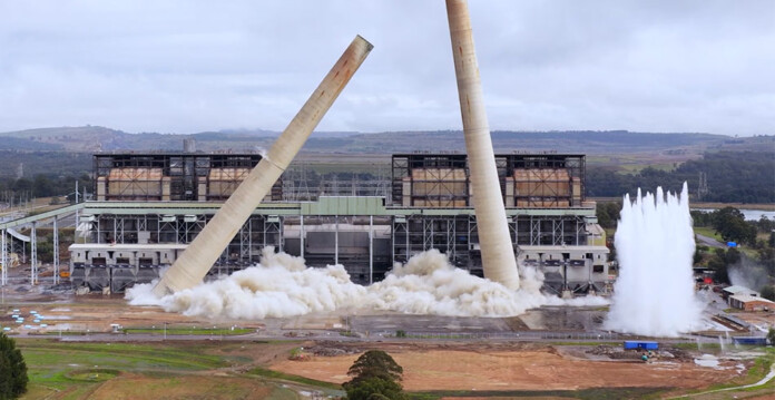 A video still captures the demolition of two giant chimney stacks at a coal-fired power station