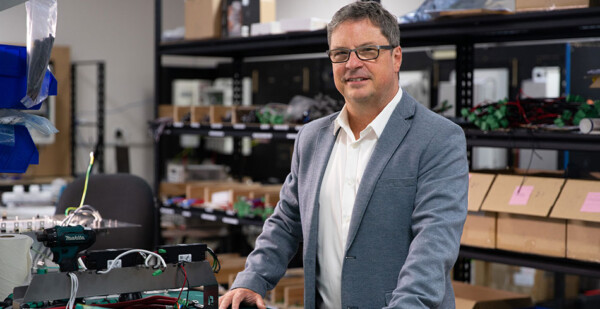 Man wearing glasses and business attire stands with equipment in warehouse