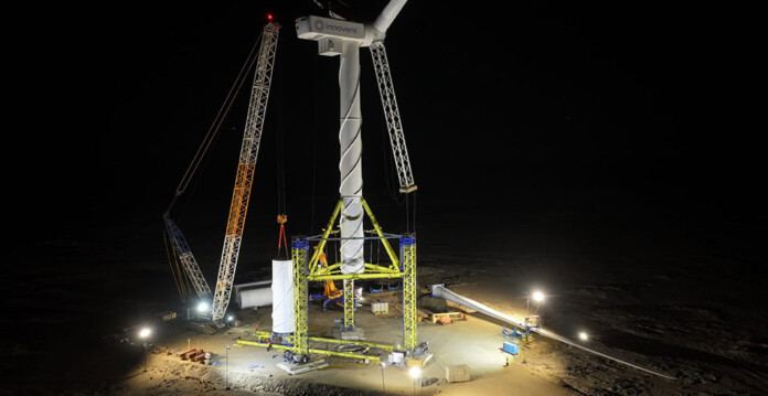Crane-less wind turbine installation system lit up by lighting at night
