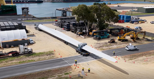 Large wind turbine blade being moved from a ship at a port