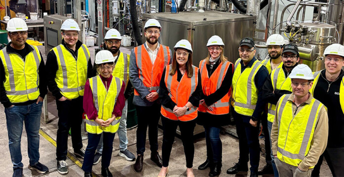 A team of energy specialists wearing high-vis vests and hard hats gathered in an energy facility. (Source: Sicona Battery Technologies)