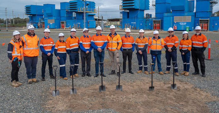 Executives in high-vis vests and hard hats break ground with shovels at project site