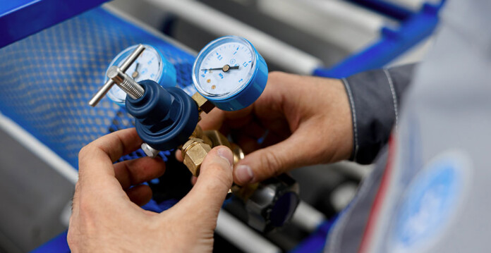 compressed-air Close-up of man tweaking gauge on air compressor
