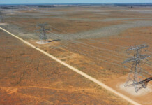 EnergyConnect completed after delays, cost blowouts Transmission towers along dirt road in rural area with reddish dirt