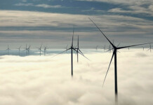 Australia’s largest wind farm passes 1GW generation output dozens of wind turbines above cloud line with blue sky overhead