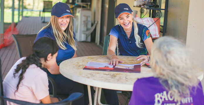 Two female energy network employees talk to two First Nations women at a table