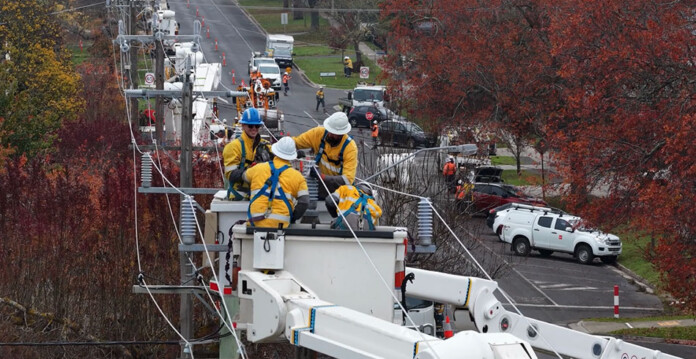Electricity crews in lift cranes work on electricity lines in rural town