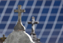 Bold energy campaign proposes ‘solar cemeteries’ Crosses on the headstone of graves in the foreground with distant solar panels blurred in the background