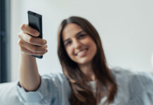 Three hours of free power sounds good, but is Solar Sharer fair? Smiling woman with long brown hair sits on couch in living room and uses a remote control