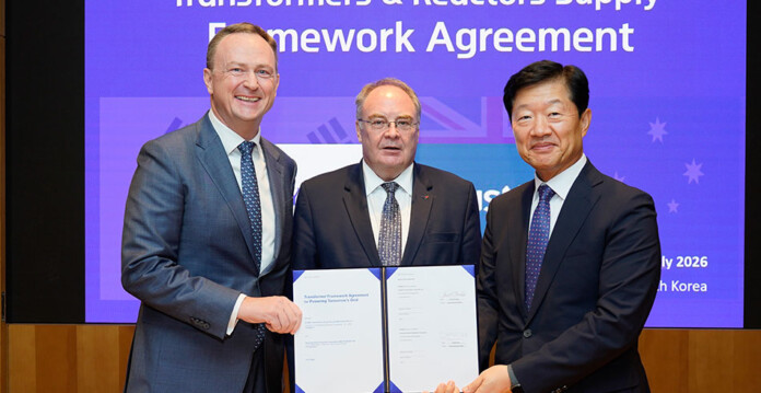 Three make energy executives in suits hold up signed agreement papers while posing for photograph