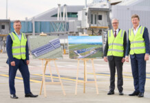 Western Sydney International Airport to run on renewables Three male executives in high-vis vests stand with airport plans outside terminal buildings