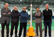 New floating turbine design to make offshore wind cheaper Five researchers stand with a floating wind turbine prototype at a wave testing facility in China