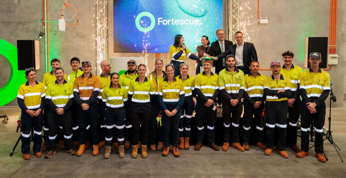 Group of apprentices poses for photo in front of Fortescue logo on screen