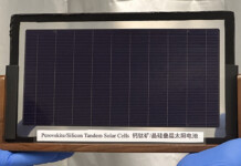 Solar breakthrough cuts scarce metal in tandem cell Blue-gloved hands hold up tandem solar cell prototype