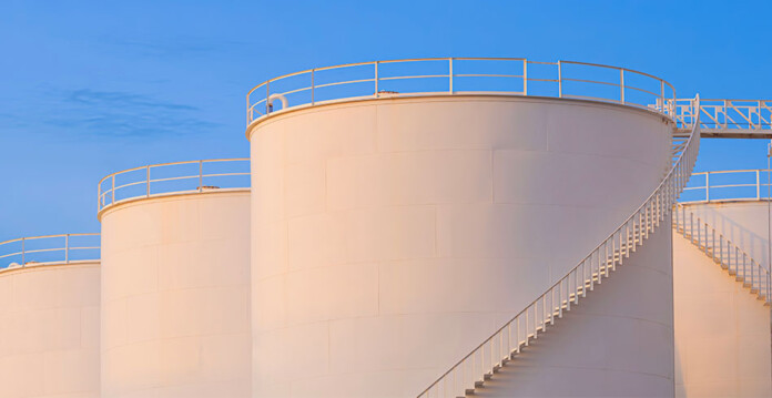 Massive crude oil storage tanks at an oil refinery with blue sky overhead
