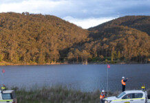 Pumped hydro and solar project to revive Hunter mine site Large water reservoir with green hills in background, and site survey vehicles in foreground